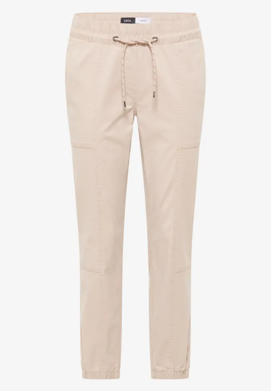 Pantalon beige léger, taille élastique avec cordon, coupe fuselée et bas de jambe élastiqué.