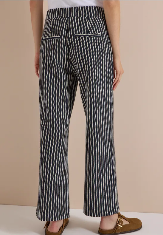 Rückansicht in ausgestellten Hosen mit blauen und weißen Streifen, Pattentaschen und Mokassins.