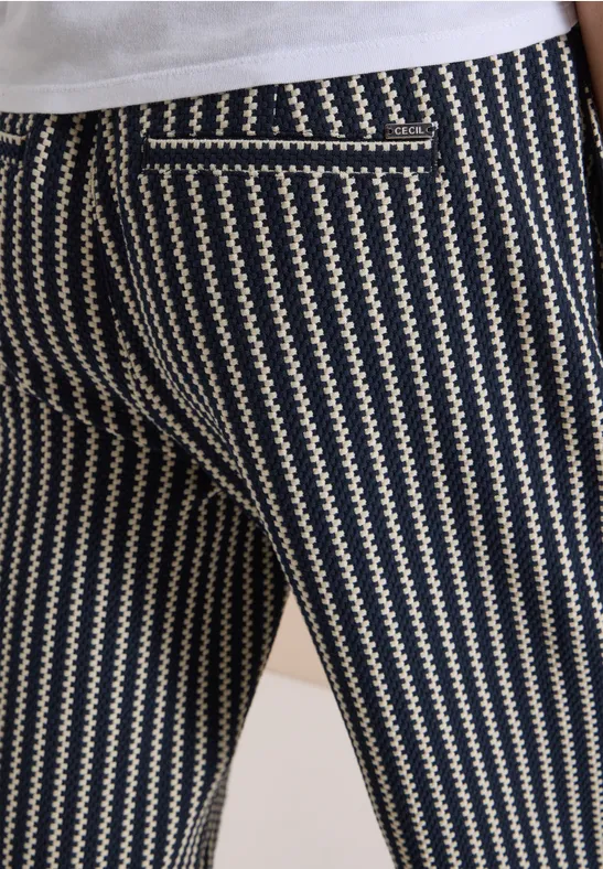 Rückenansicht einer Person mit blau-beigen Zickzack-Hose und einer sichtbaren Gesäßtasche.