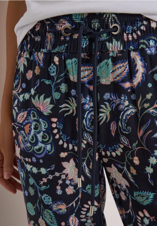 Hose aus dunkelblauem Stoff mit buntem Paisley- und Blumenmuster und Kordelzug.
