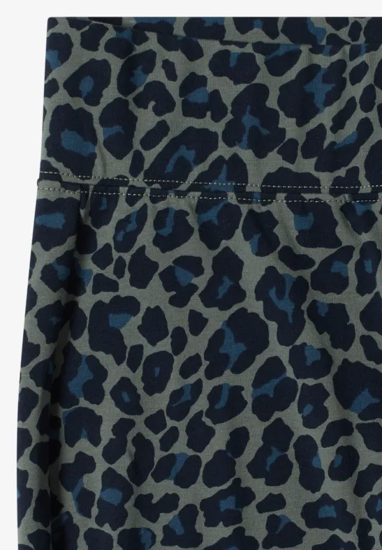 Close-up van grijs-blauw textiel met blauw luipaardpatroon en zichtbare naad.