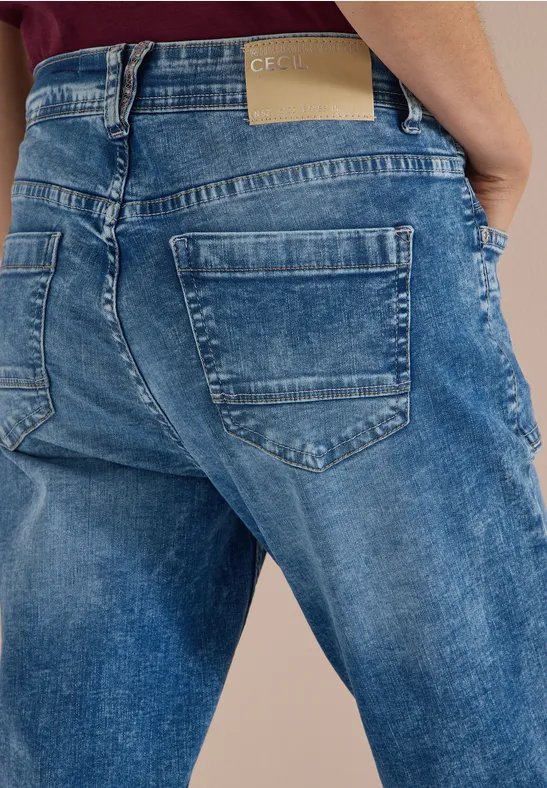 Rückansicht einer Person in locker sitzenden blauen Jeans mit zwei Gesäßstaschen und sichtbarem Label am Bund.