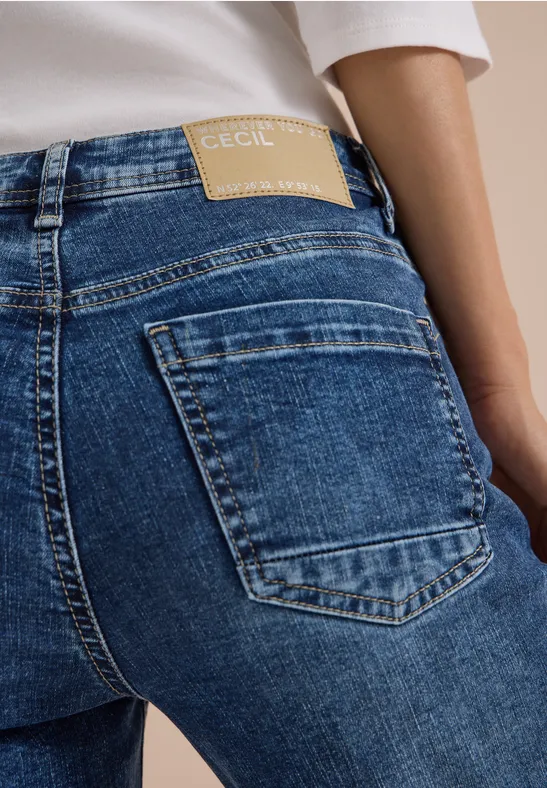 Vue arrière d’une personne portant un jean bleu avec étiquette de marque à la taille.