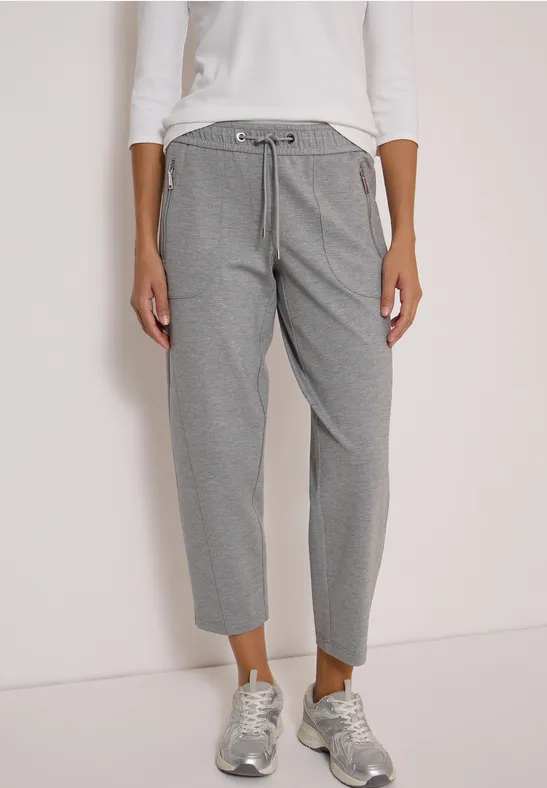 Frau trägt graue Hose mit Kordelzug und silberne Sneaker.