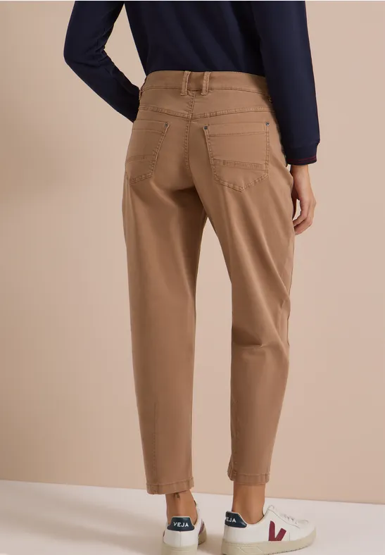 Frau von hinten trägt beige Chino-Hosen mit Umschlag, dunkelblaues Oberteil und weiße Sneakers.