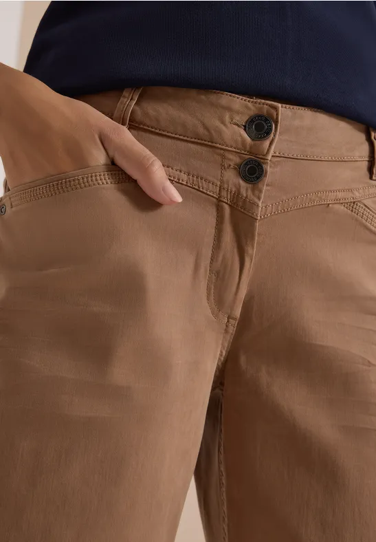 Braune Hose mit zwei Knöpfen vorne, Hand steckt in der Seitentasche.