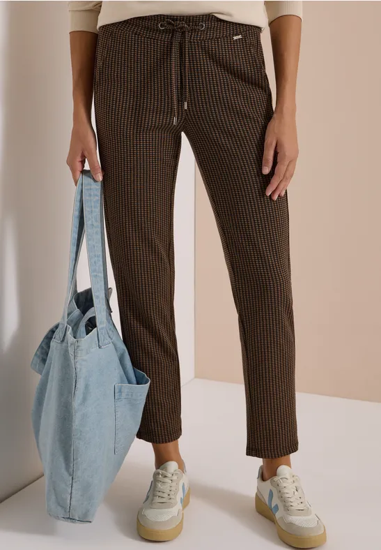 Personne porte un pantalon marron foncé à fines rayures avec cordon, des baskets blanches et un sac en jean bleu.