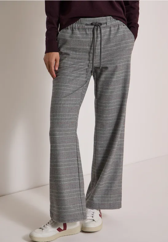 Graue karierte Hose mit Kordelzug, weitem Bein und weißen Sneakern.