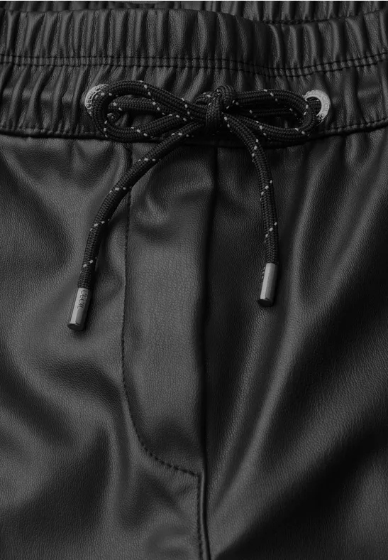 Schwarze Kunstlederhose mit elastischem Bund und schwarzen Kordeln mit Reflektorpunkten.