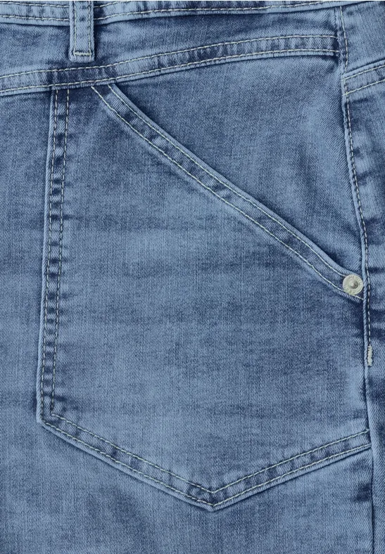 Close-up van een blauwe spijkerbroekzak met zichtbare stiknaden en metalen klinknagel.