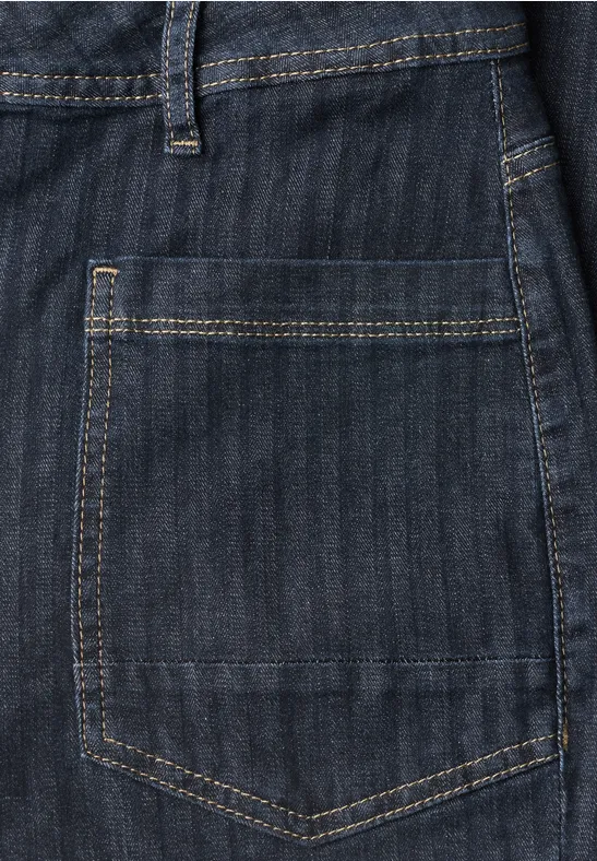 Nahaufnahme einer Rückentasche aus dunkelblauem Denim-Jeansstoff mit goldfarbener Naht.