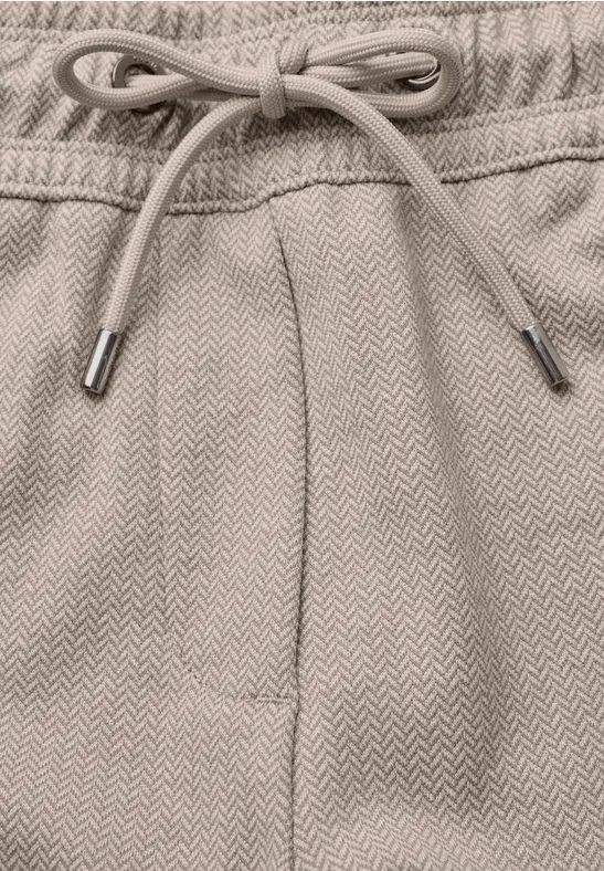 Nahaufnahme eines beigen Sweatpants-Bunds mit Kordelzug und subtiler Fischgrätenstruktur.