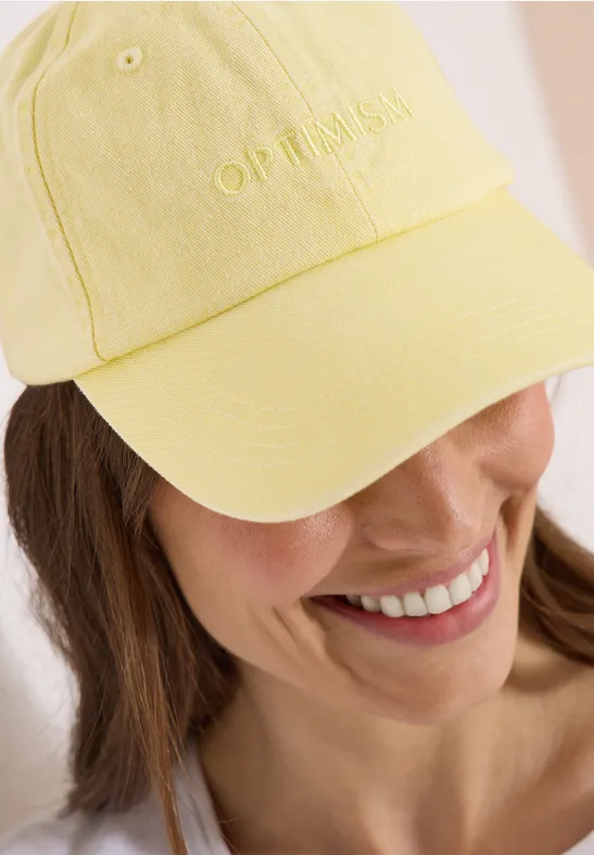 Frau trägt hellgelbe Baseballkappe, Gesicht unscharf