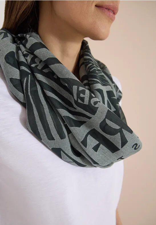 Nahaufnahme einer Frau in weißem T-Shirt, die einen grauen Schal mit dunkler Schrift trägt.