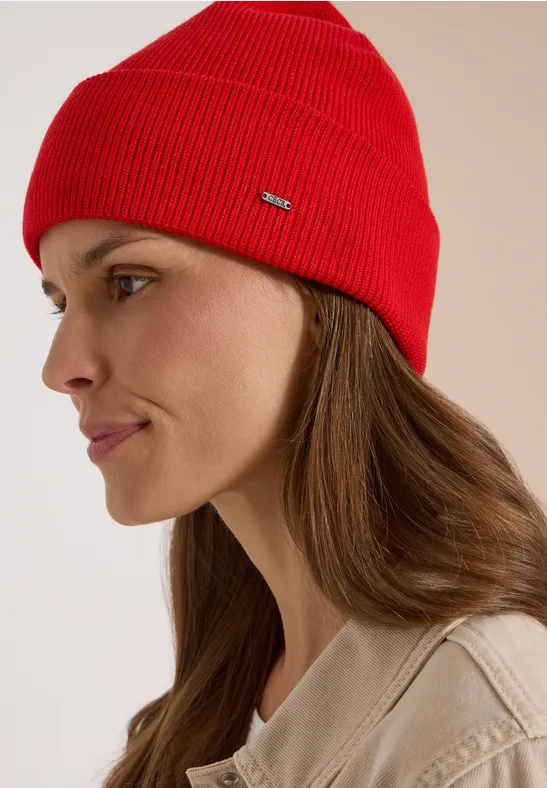 Portrait de profil d’une femme coiffée d’un bonnet rouge et portant un manteau clair