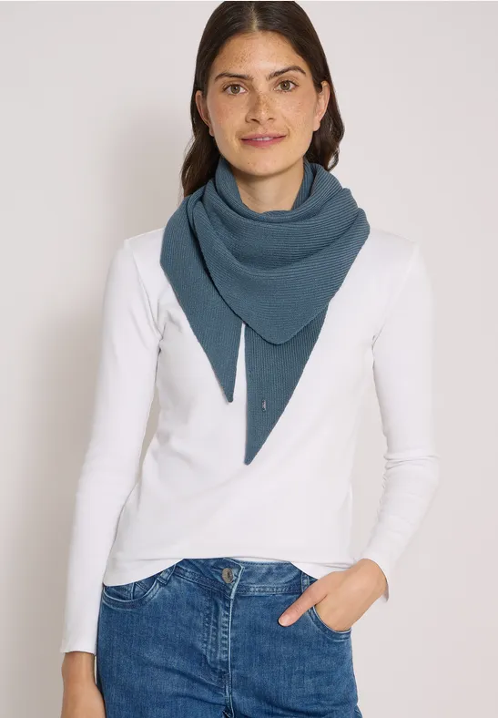 Femme souriante en t-shirt blanc à manches longues et châle bleu triangulaire sur fond clair