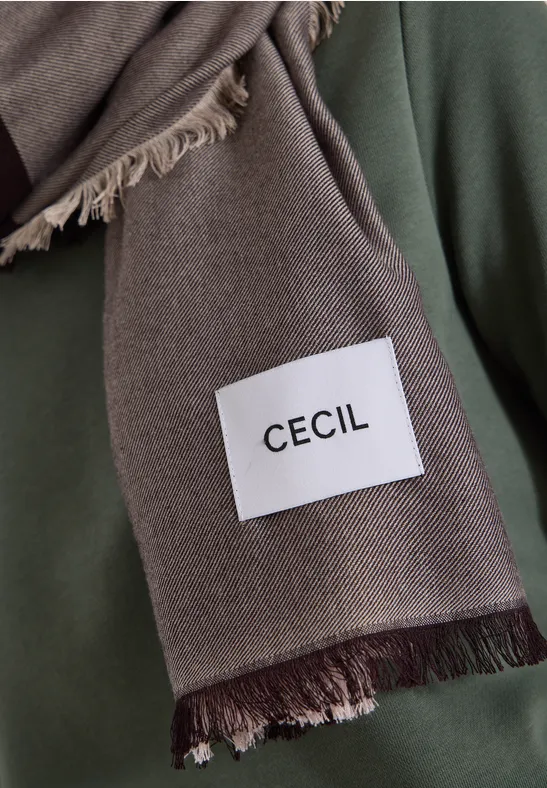 Une écharpe brune à franges avec une étiquette blanche indiquant « CECIL ».