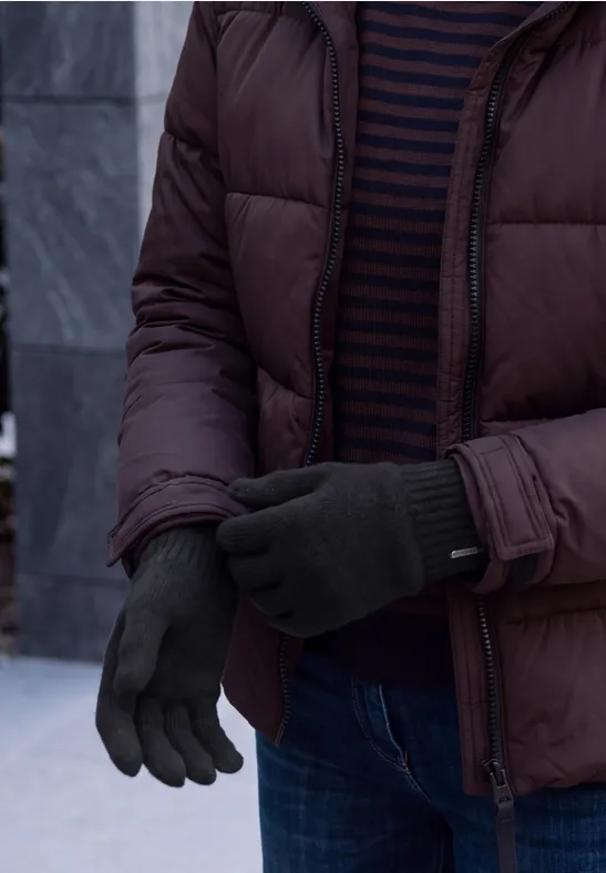 Personne porte une doudoune marron, un pull rayé et des gants foncés à l'extérieur.