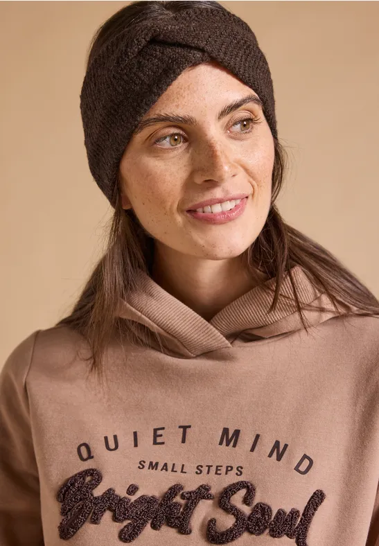Kobieta w brązowej opasce i bluzie patrzy w bok; napis 'Quiet Mind Small Steps Bright Soul'.