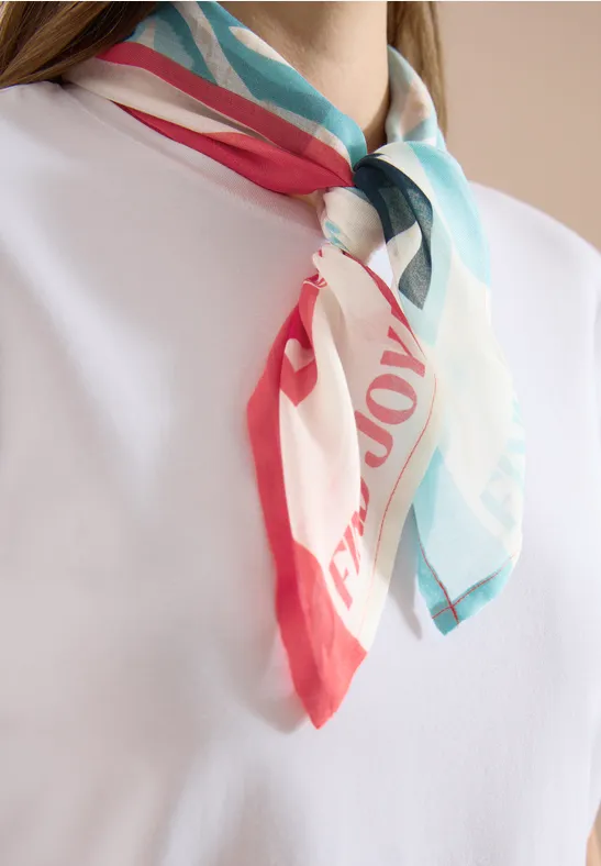 Wit T-shirt met een kleurrijk sjaaltje (rood, turkoois en wit) elegant geknoopt om de hals