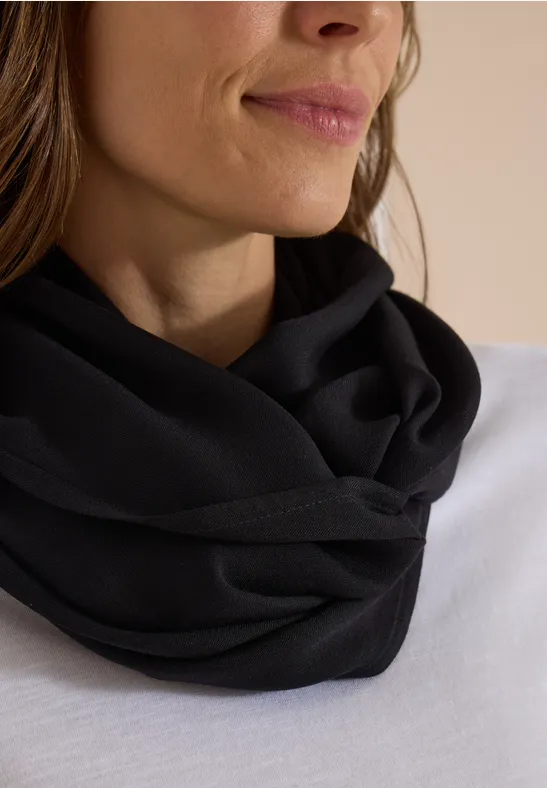 Gros plan d'une femme portant un tour de cou noir sur un haut blanc.