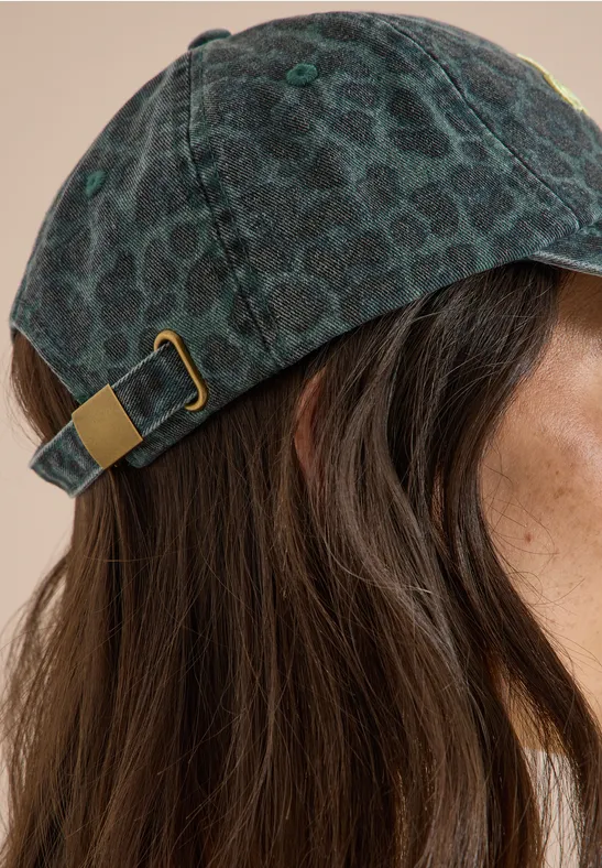 Seitenansicht einer Frau mit braunen Haaren und dunkelgemustertem Basecap.