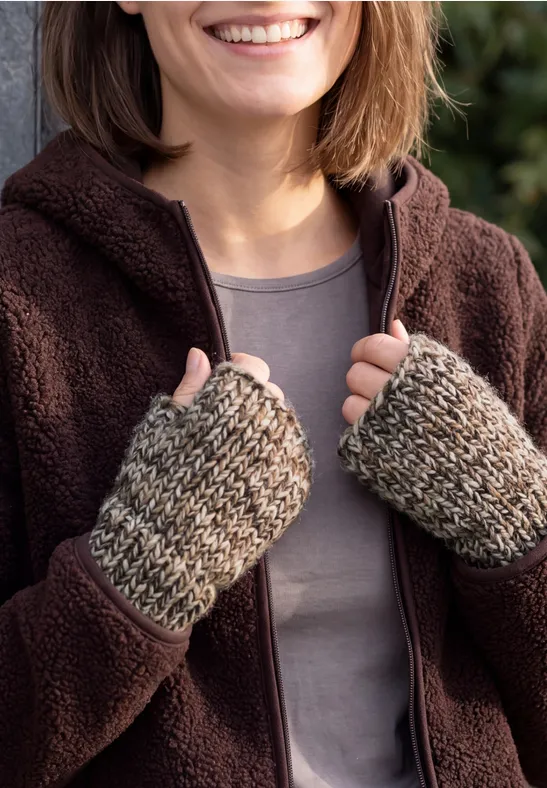 Nahaufnahme einer lächelnden Person in Fleecejacke und gestrickten Handstulpen, die die Jacke hält.