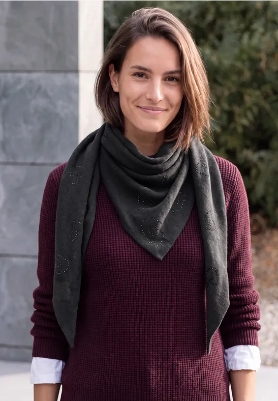 Eine lächelnde Frau mit kurzem braunem Haar, trägt einen dunkelgrünen Schal und einen weinroten Pullover.