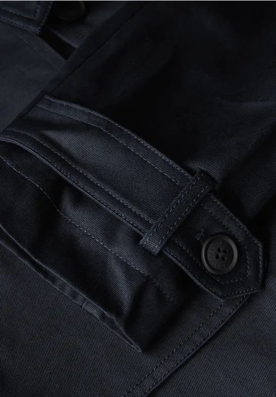 Close-up van een donkerkleurige jaszak met een knoop.