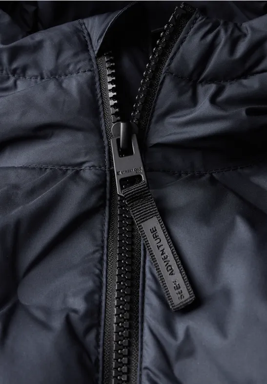 Gros plan d'une fermeture éclair noire sur une veste matelassée.
