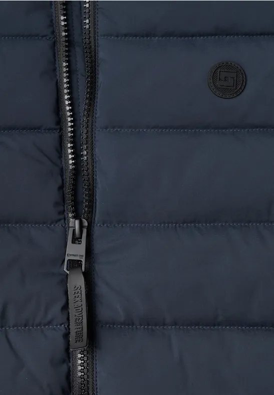 Nahaufnahme einer dunkelblauen, gesteppten Jacke mit Reißverschluss und kleinem, runden Logo.