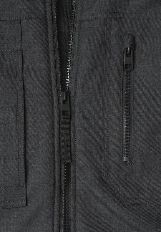 Schwarzgraue Jacke im Nahblick, erkennbarer Reißverschluss und schräge Brusttasche.