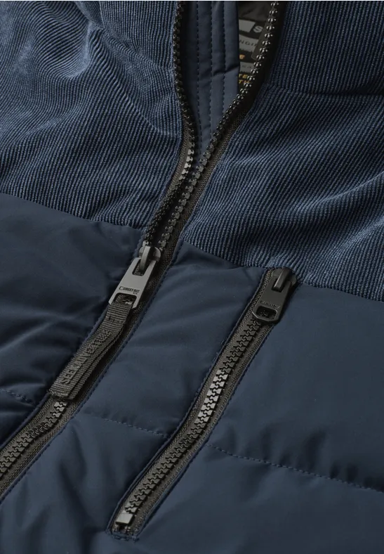 Close-up van een donkerblauwe jas met twee ritsen en verschillende stoftexturen.