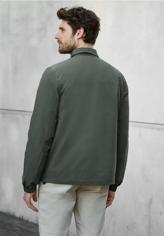 Ein Mann mit grüner Jacke und heller Hose steht mit dem Rücken zur Kamera.