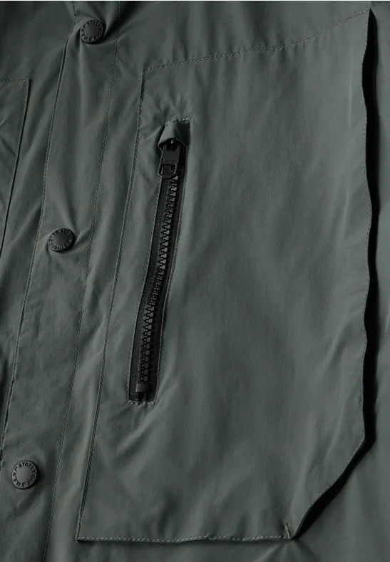 Nahaufnahme einer grünen Jacke mit Reißverschluss und Knöpfen.