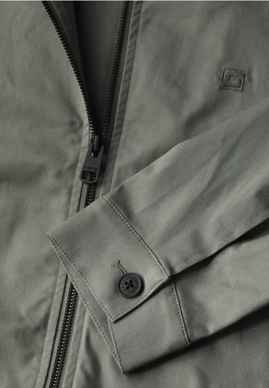 Olivegrüne Jacke mit Reißverschluss und Ärmelabschlüssen aus Snaps, Detailansicht.