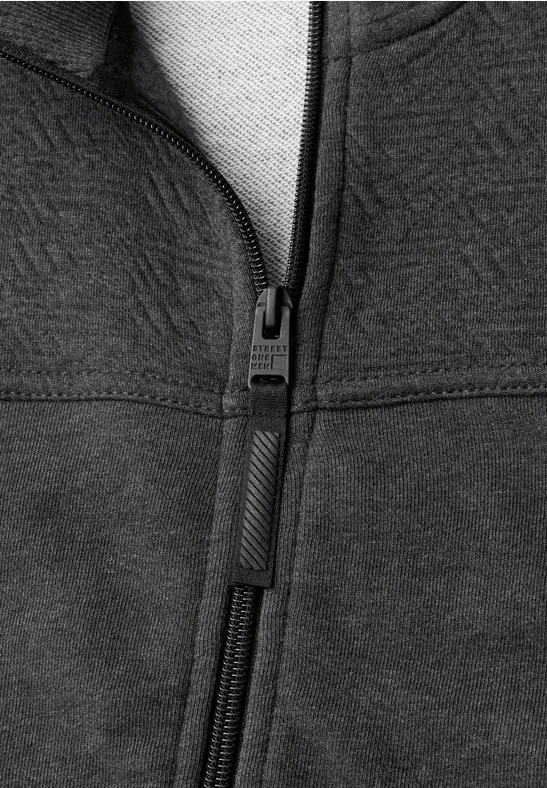 Nahaufnahme einer dunkelgrauen Jacke mit Reißverschluss und sichtbaren Nähten.