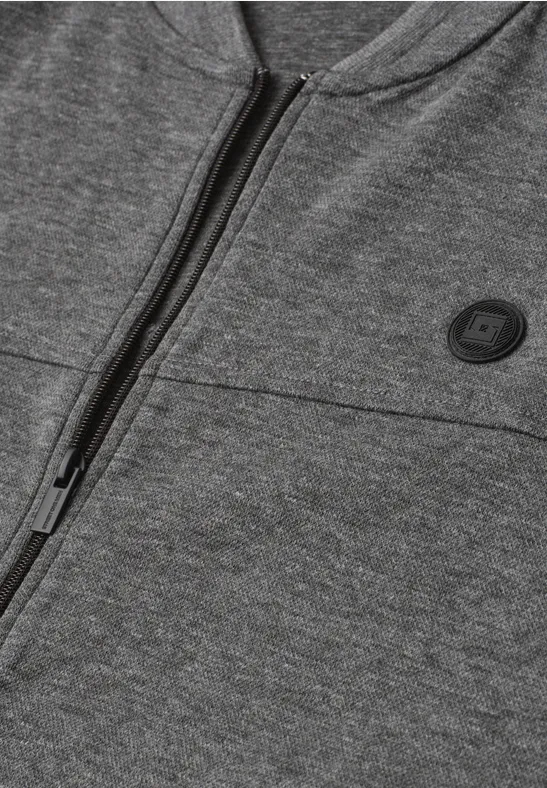 Close-up van een grijze hoodie met rits en ronde logopatch.