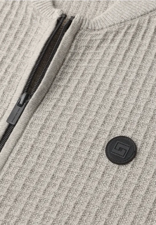 Beige geripptes Strickmaterial mit schwarzem Reißverschluss und rundem Logo-Patch