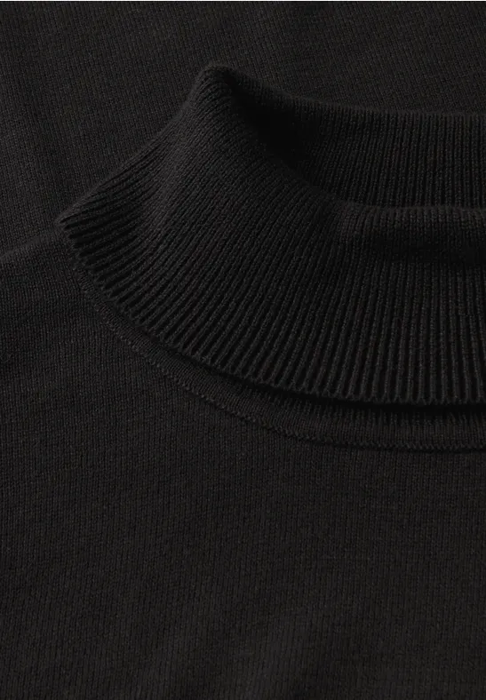 Nahaufnahme eines schwarzen Rollkragenpullovers aus Strick.