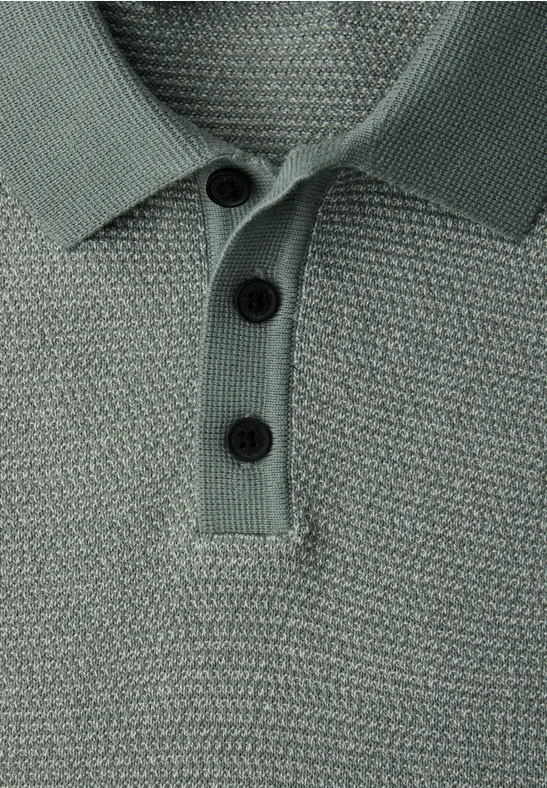Close-up van een groen-grijs gebreid poloshirt met knoopsluiting en drie zwarte knopen.