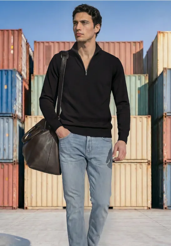 Een casual geklede man met schoudertas staat voor kleurrijke containers.