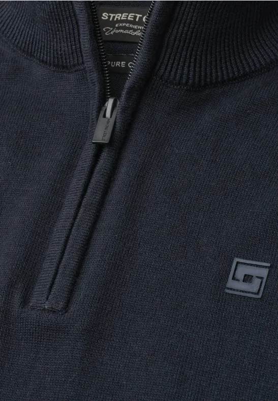 Donkerblauwe gebreide trui met korte ritssluiting bij de kraag en klein logo-patch op de borst.