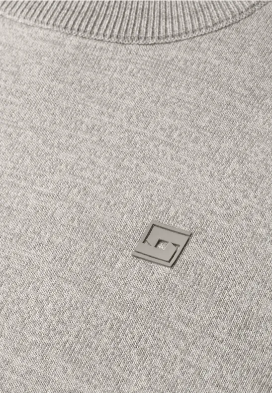 Grauer Strickpullover mit kleinem Metall-Logo in G-Form auf der Brust.