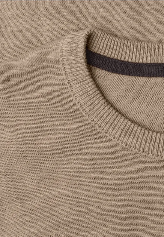 Close-up van een beige gebreide trui met ronde hals en geribbelde boord