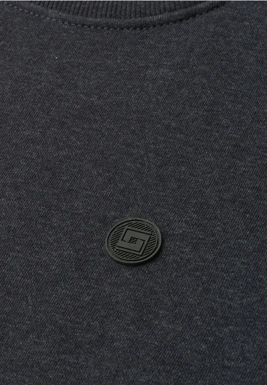 Dunkelgraues Shirt mit kleinem, rundem, schwarzem Logo-Patch mittig.