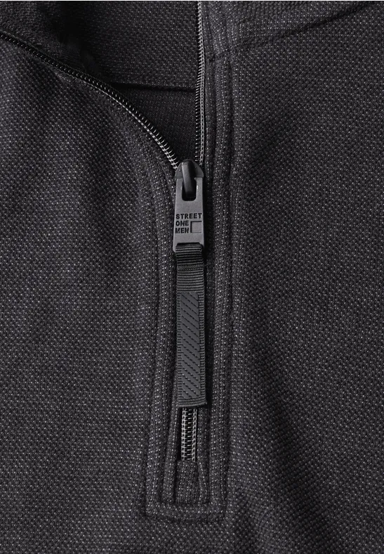 Nahaufnahme eines schwarzen Reißverschlusses auf grob gewebtem Textil.
