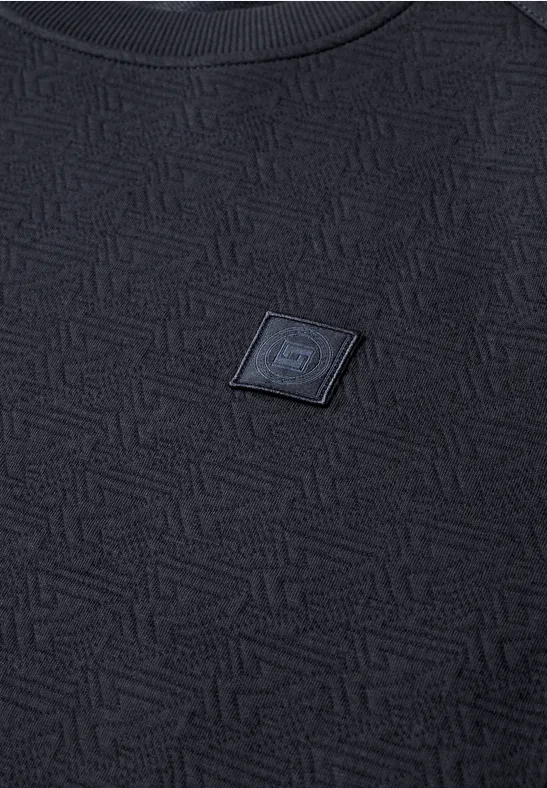 Schwarzes, strukturiertes T-Shirt mit geometrischem Muster und mittig angebrachtem Logo-Patch.