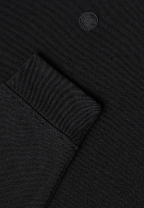 Nahaufnahme eines schwarzen Kleidungsstücks mit eingenähter Tasche und dezenter Logoprägung