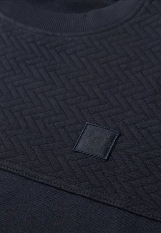 T-shirt bleu foncé avec motif zigzag texturé et petit patch carré marqué d'un G.